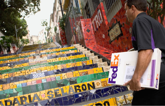 Empleado de FedEx llevando una caja y subiendo una escalera